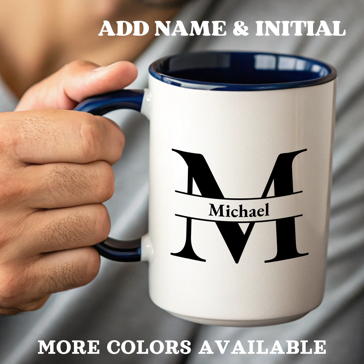 An accent color ceramic mug handheld, with a navy interior, navy handle, and a black graphic of a stylized letter M with a banner reading 'Michael' on the front. 