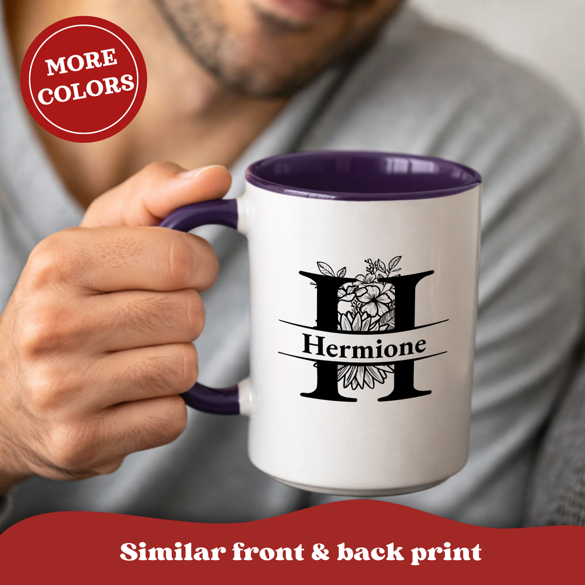 A person holding a white ceramic mug with a purple interior and handle. The mug has a black floral monogram design with the word 'Hermione' printed on it.