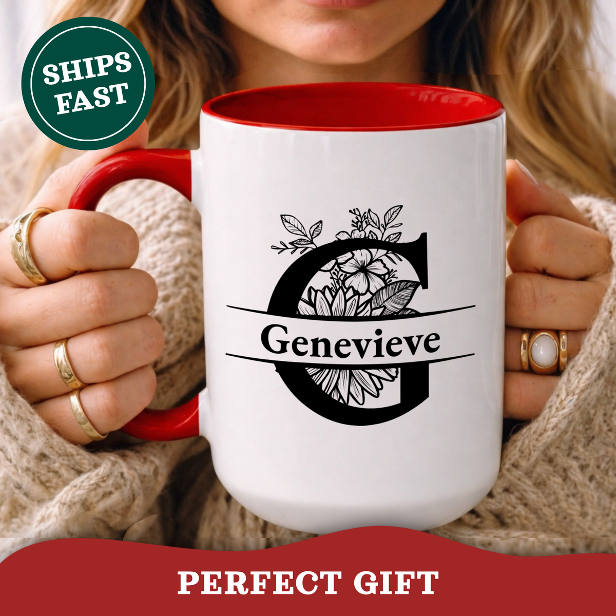 A person holds a white ceramic mug with a red interior and handle. The mug features a large black floral letter G and the name 'Genevieve' across the front.
