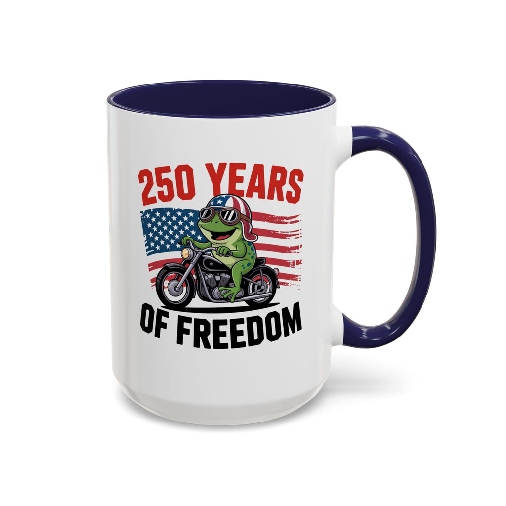 A white ceramic mug with a dark navy blue interior and handle, featuring a graphic of a green frog riding a motorcycle in front of an American flag with the text '250 YEARS OF FREEDOM'.
