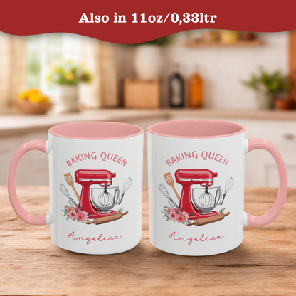 Two white ceramic 11oz mugs with pink interiors and handles sit on a wooden table in a blurred kitchen setting. Each mug is printed with a red stand mixer illustration, baking tools, pink flowers, the words 'BAKING QUEEN,' and the name 'Angelica.
