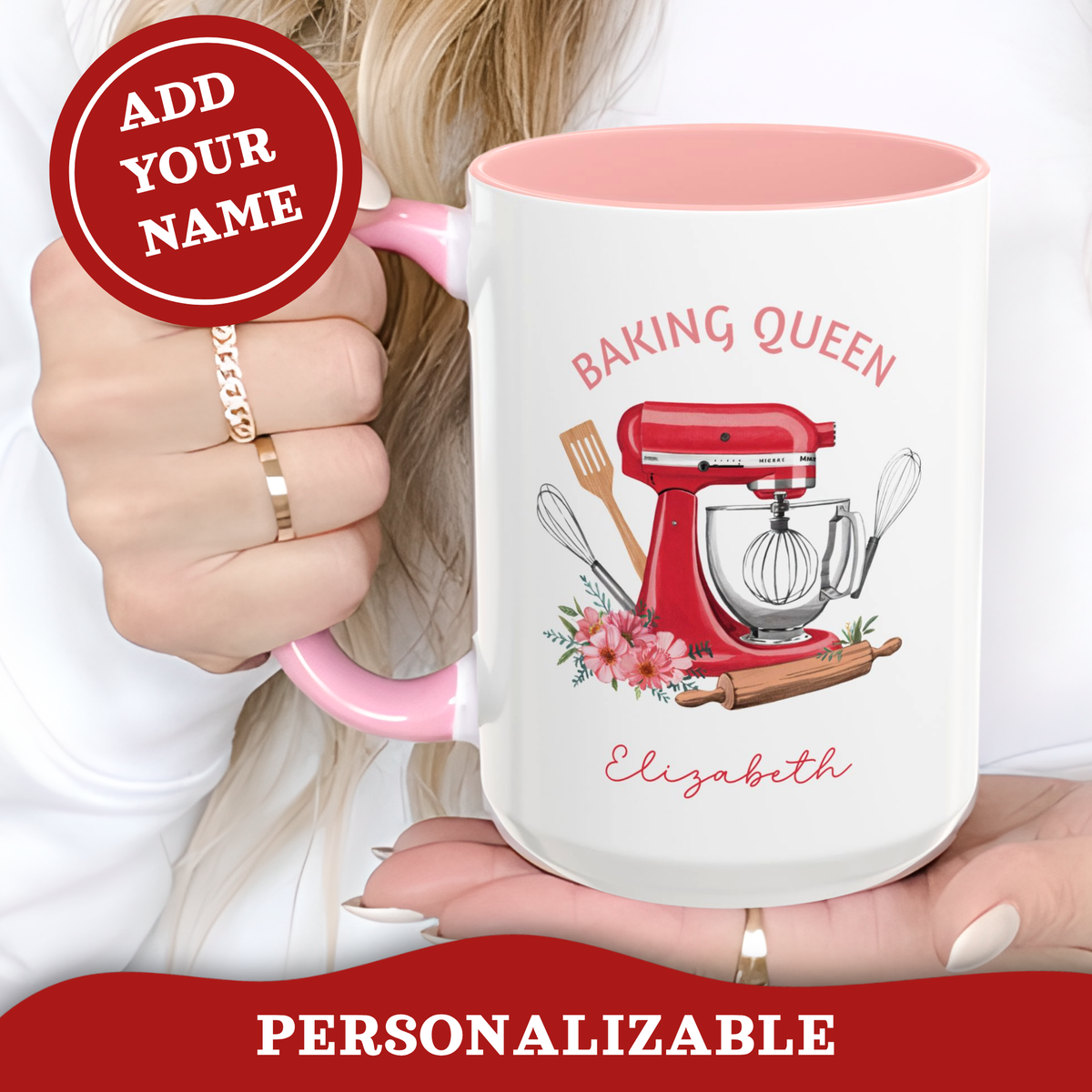 A white ceramic 15oz mug with a pink handle and interior, featuring a red stand mixer illustration and the text 'BAKING QUEEN' and 'Elizabeth'. A person's hand holds the mug, with a red circular badge reading 'ADD YOUR NAME' and a red banner at the bottom reading 'PERSONALIZABLE'.