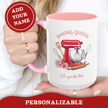 A white ceramic 15oz mug with a pink handle and interior, featuring a red stand mixer illustration and the text 'BAKING QUEEN' and 'Elizabeth'. A person's hand holds the mug, with a red circular badge reading 'ADD YOUR NAME' and a red banner at the bottom reading 'PERSONALIZABLE'.