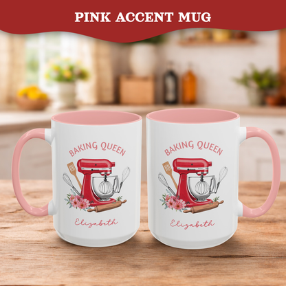 Two white ceramic 15oz mugs with pink interiors and handles, displayed side by side on a wooden table. Each mug features a printed illustration of a red stand mixer, baking utensils, flowers, and the text 'BAKING QUEEN Elizabeth'.