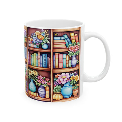 A white ceramic 11oz mug featuring a colorful wrap-around illustration of a wooden bookshelf filled with books, flowers, and vases, shown on a plain white background. A subtle personalized name is put on one of the book spines. Right handle view.