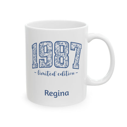 A white ceramic 11oz mug with a blue floral patterned '1987' design, featuring the text '~ limited edition ~' and the name 'Regina' printed below, shown on a plain white background. Right handle view.