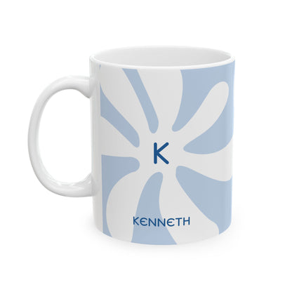 A white ceramic 11oz mug featuring a light blue retro sunburst pattern, a navy blue monogram letter 'K' in the center, and the name 'KENNETH' printed in navy blue at the bottom. Left handle view.
