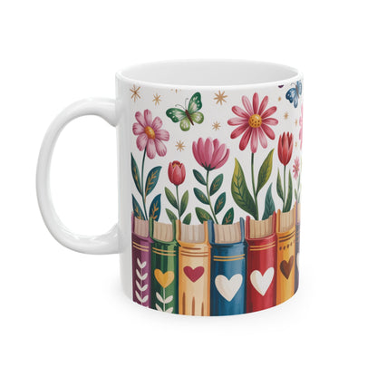 A white ceramic 11oz mug featuring a colorful illustration of flowers blooming from book spines, with butterflies and small star accents on a white background. Left handle view.