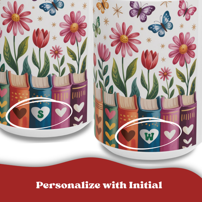 Two white 15oz mugs shown on a white background with a red banner at the bottom reading 'Personalize with Initial.' The cups feature a colorful floral and butterfly print above a row of book spines, with heart details and initial letters S and W highlighted with white circles.