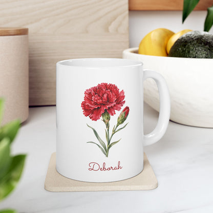 Carnation birth flower personalized ceramic mug, 11oz, on a wooden coaster with fruit bowl in background.