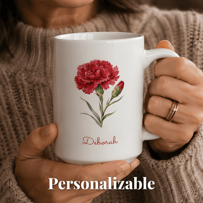 A woman holds a white ceramic mug with carnation birth flower and personalized name at bottom.