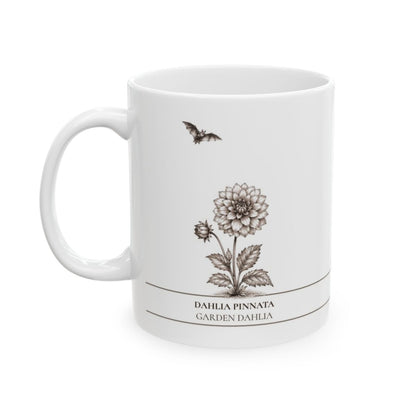 A white ceramic mug featuring a botanical illustration of a Dahlia Pinnata flower with a small bat above it, and the text 'DAHLIA PINNATA' and 'GARDEN DAHLIA' printed below.