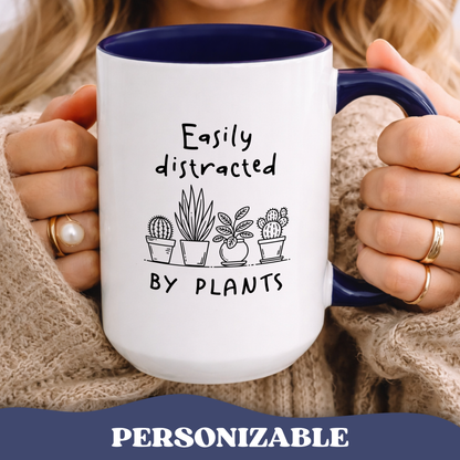 Person holding Easily Distracted by Plants accent mug with navy interior and cacti graphic.