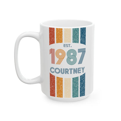 A white ceramic 15oz mug with a colorful retro design featuring vertical stripes in orange, beige, teal, and blue, with the text 'EST. 1987 COURTNEY' printed on the front. Left handle view.