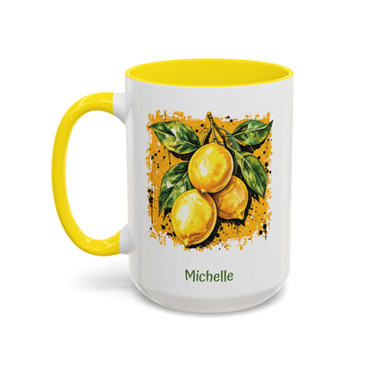 A white ceramic 15oz mug with a bright yellow handle and yellow interior, featuring a printed illustration of three yellow lemons with green leaves on darker yellow textured background. The name 'Michelle' is printed in green below the artwork. Left handle view.