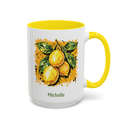 A white ceramic 15oz mug with a bright yellow handle and yellow interior, featuring a printed illustration of three yellow lemons with green leaves on darker yellow textured background. The name 'Michelle' is printed in green below the artwork. Right handle view.
