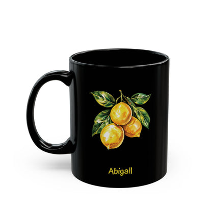 A black ceramic 11oz mug featuring a printed illustration of three yellow lemons with green leaves and the name 'Cynthia' in yellow text below, shown on a plain white background. Left handle view.