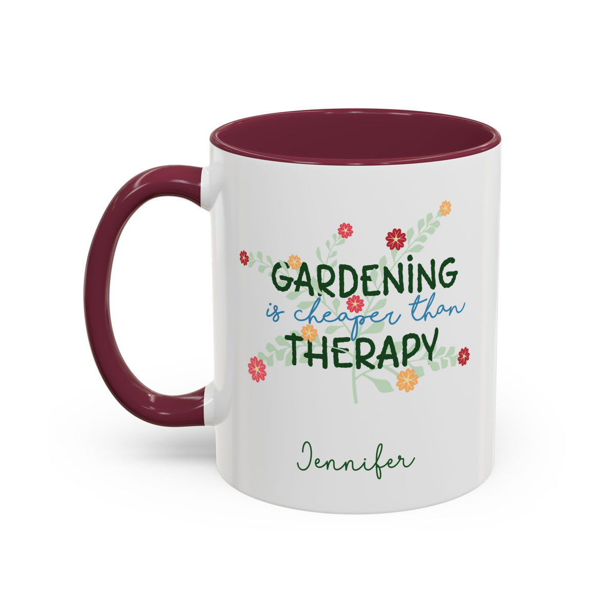 A white ceramic 11oz mug with a maroon colored handle and interior, featuring the printed phrase 'GARDENING is cheaper than THERAPY' in green and blue script with small colorful flowers and the name 'Jennifer' below. Left handle view.