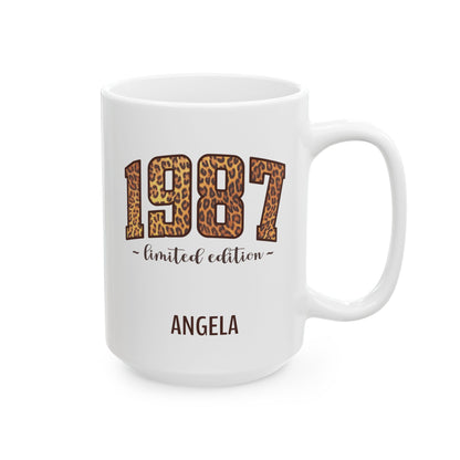 A white ceramic 15oz mug with a custom design featuring the year '1987' in a leopard print pattern, the phrase '~ limited edition ~' underneath, and the name 'ANGELA' printed below in brown. Right handle view.