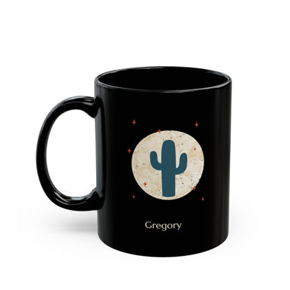 A 11oz glossy black ceramic mug, featuring a printed graphic of a teal cactus inside a beige circle with small red stars, and the name 'Gregory' printed below, left handle view.
