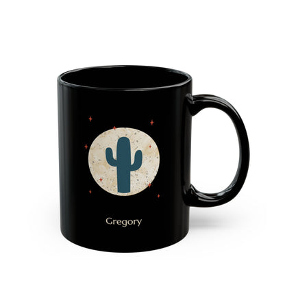 A 11oz glossy black ceramic mug, featuring a printed graphic of a teal cactus inside a beige circle with small red stars, and the name 'Gregory' printed below, right handle view.