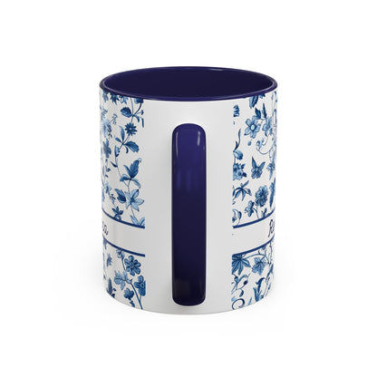 A white ceramic 11oz mug with a blue floral and butterfly pattern on the exterior, featuring a solid dark blue interior and a matching dark blue handle, shown on a plain white background. View of the handle.