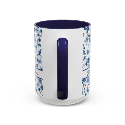 A white ceramic 15oz mug with a dark blue interior, a dark blue handle, and blue floral patterns printed on the sides. View of the handle.