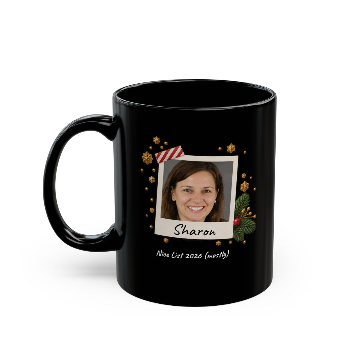 A black ceramic 11oz mug with a custom printed holiday design featuring a photo frame, gold ornaments, and the name 'Abigail' with the text 'Nice List 2026 (mostly)' on a white background. Left handle view.