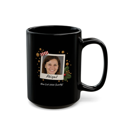 A black ceramic 15oz mug with a custom printed holiday design featuring a photo frame, gold ornaments, and the name 'Abigail' with the text 'Nice List 2026 (mostly)' on a white background. Right handle view.