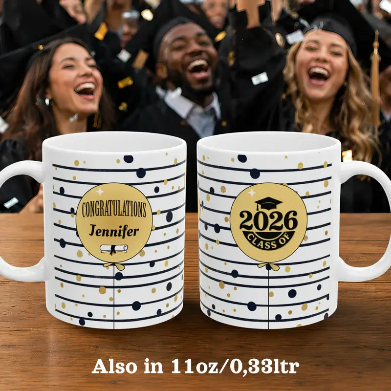 Two personalized graduation mugs on a table with celebrating students in the background