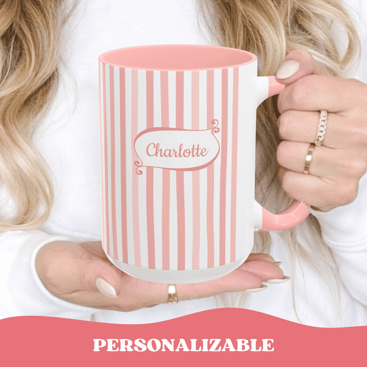 A person holds a white ceramic 15oz mug with pink vertical stripes and a pink handle, and a personalized name in a playful frame reading 'Charlotte'. A banner at the bottom says 'PERSONALIZABLE'.