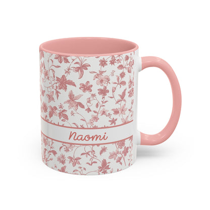 A white ceramic 11oz mug with a pink floral chinoiserie pattern, a pink handle, and a pink interior. A white band around the middle features the name 'Joanna' in pink script. Right handle view.