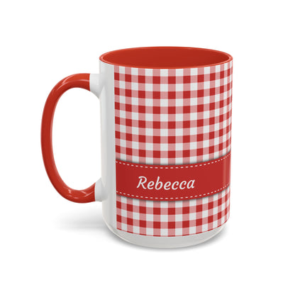 A white ceramic 15oz mug with a red and white gingham check pattern, a solid red handle and interior, and a red horizontal band around the middle featuring the name 'Rebecca' in white script. Left handle view.