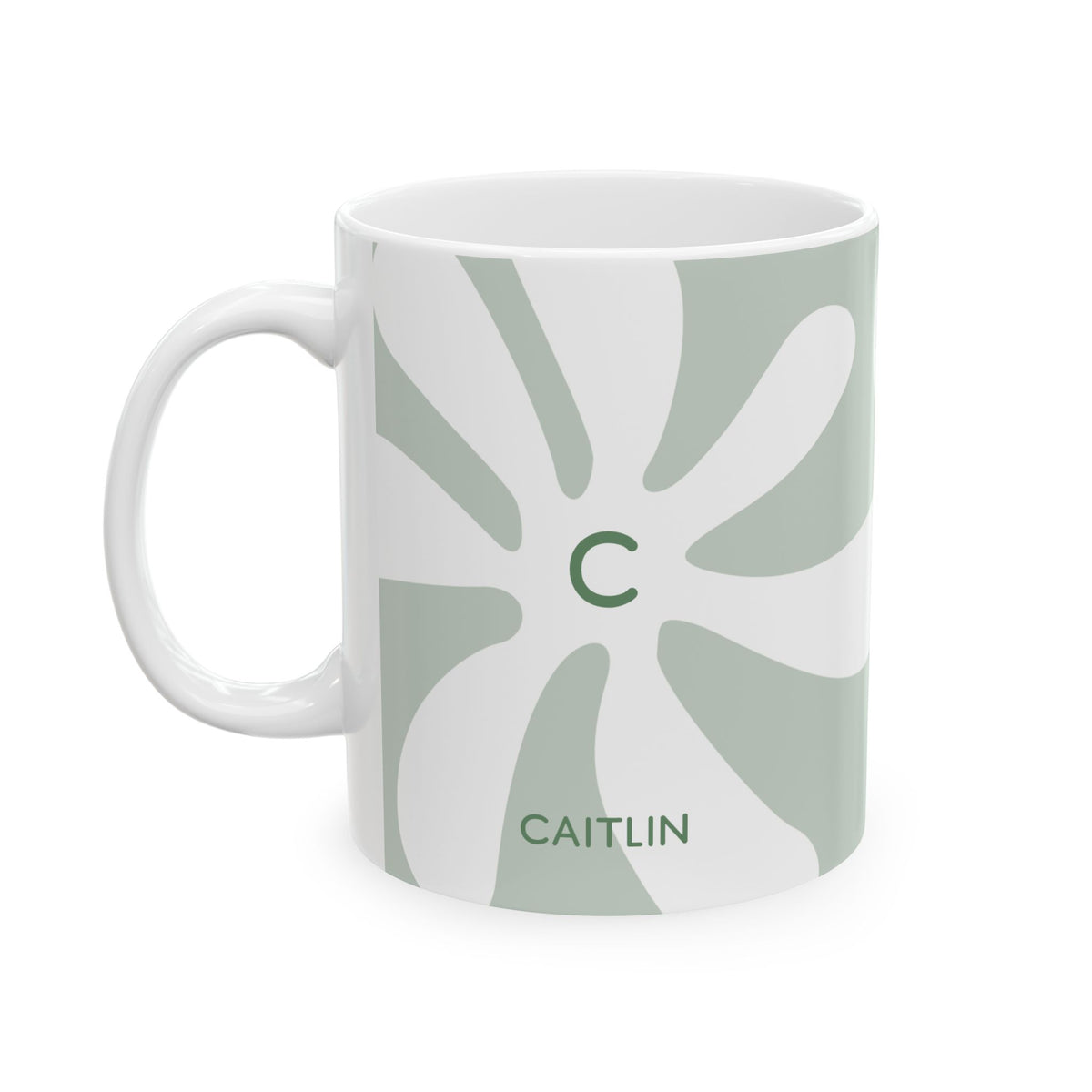 A white ceramic 11oz mug featuring a minimalist retro design with a light sage green abstract sunburst pattern, a green monogram letter 'C' in the center, and the name 'CAITLIN' printed in green near the bottom. Left handle view.