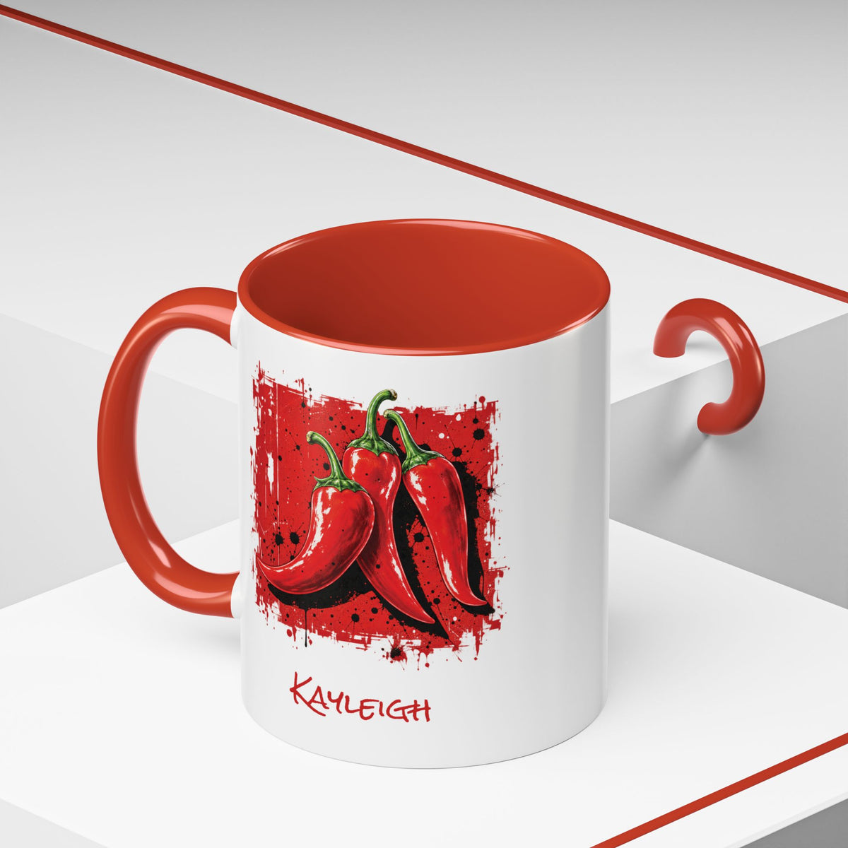 A white ceramic 11oz mug with a red interior, red handle, and red side handle, featuring a graphic of three red chili peppers on the front and the name 'KAYLEIGH' printed below in red capital script.