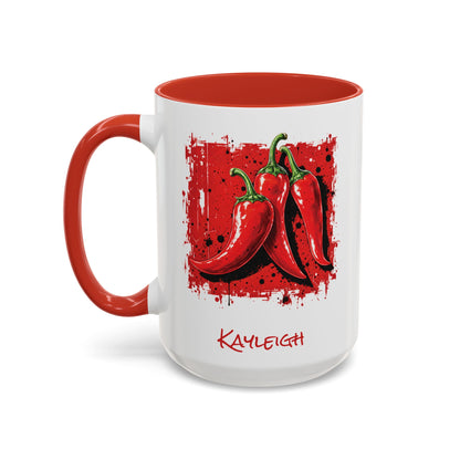 A white ceramic 15oz mug with a red interior and red handle, featuring a graphic of three red chili peppers on a red splattered square and the name 'KAYLEIGH' printed below in red. Left handle view.