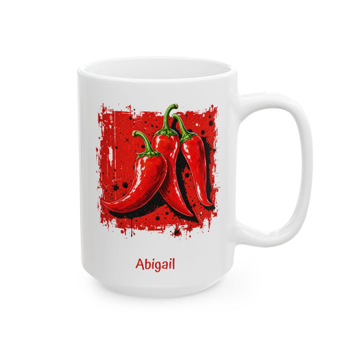 A white ceramic 15oz mug featuring a graphic print of three red chili peppers on a red splattered background, with the name 'Abigail' printed in red below the illustration. Right handle view.