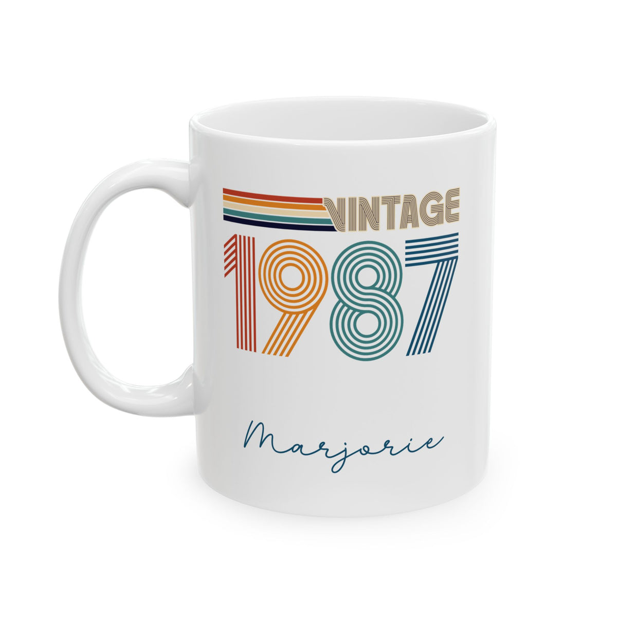 A white ceramic 11oz mug featuring a retro-style 'Vintage 1987' graphic with colorful stripes and the name 'Marjorie' written in cursive below, shown on a plain white background. Left handle view.