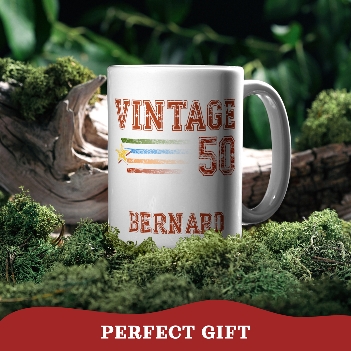 A white ceramic 15oz mug with 'VINTAGE 50 BERNARD' and a striped flag graphic in red, green, white, and blue, set in mossy forest decor with a red 'PERFECT GIFT' banner at the bottom.
