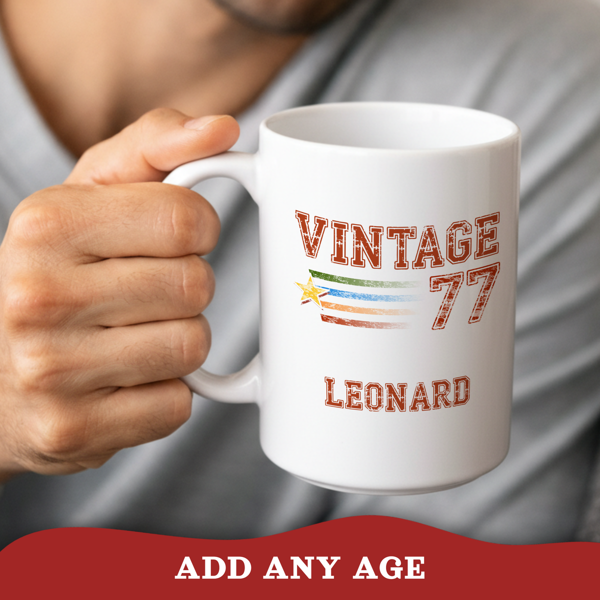 A person holds a white ceramic mug with a custom printed design that reads 'VINTAGE 77 LEONARD' with a retro flag motif. The background shows a blurred gray shirt and skin, with a red banner at the bottom reading 'ADD ANY AGE'.