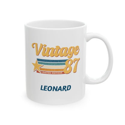 A white ceramic 11oz mug with a retro 'Vintage 87' graphic featuring gold, blue, and orange colors, and the name 'LEONARD' printed in blue below. Right handle view.