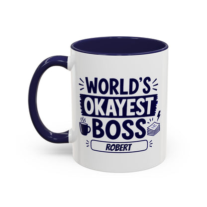 A white ceramic 11oz coffee mug with a dark navy blue interior, handle, and printed text reading 'WORLD'S OKAYEST BOSS ROBERT' in navy blue lettering, shown on a plain white background. Left handle view.