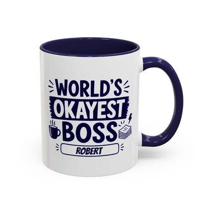 A white ceramic 11oz coffee mug with a dark navy blue interior, handle, and printed text reading 'WORLD'S OKAYEST BOSS ROBERT' in navy blue lettering, shown on a clean white background. Right handle view.