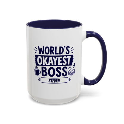 A white ceramic 15oz mug with a navy interior and handle, printed with the bold text 'World's Okayest Boss' above a name plate reading 'Steven'. Right handle view.